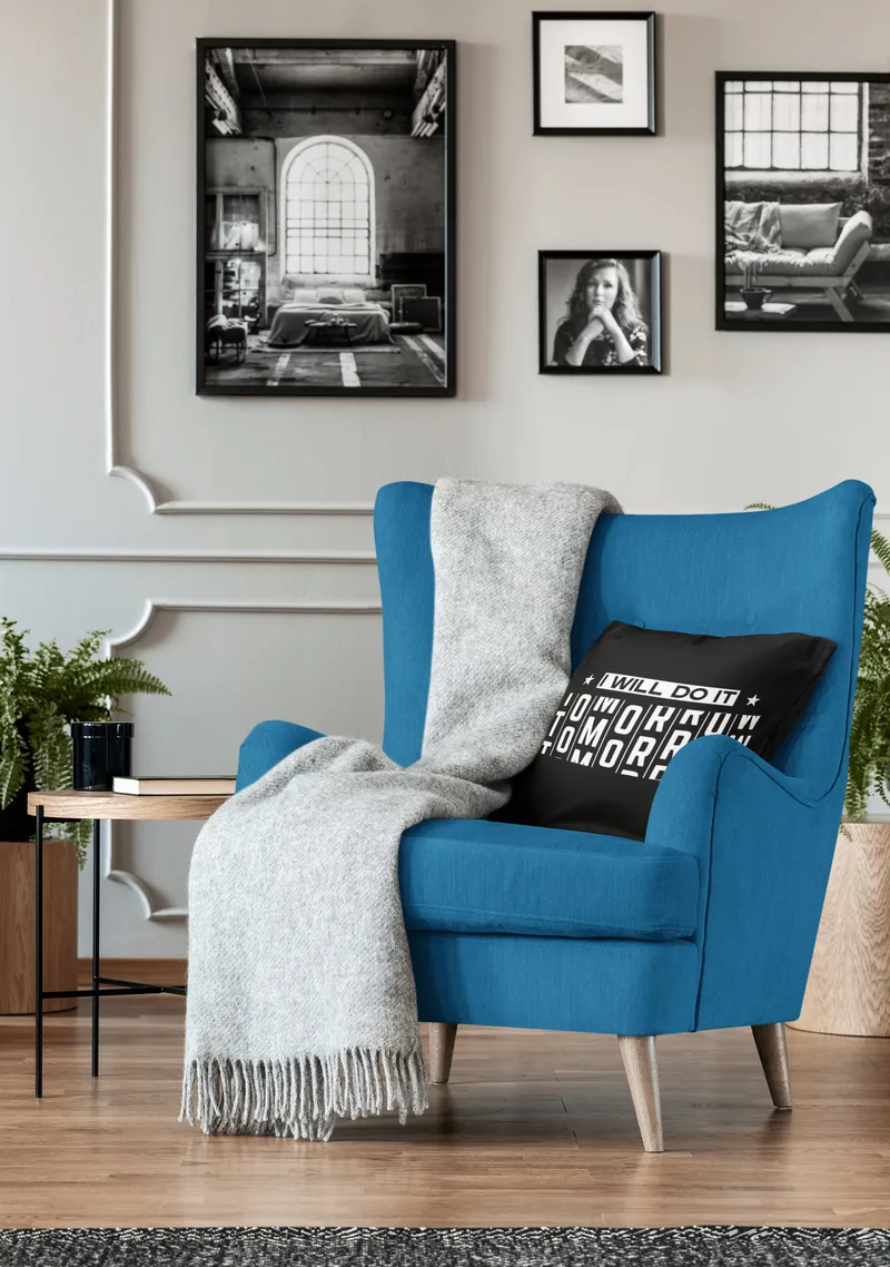Black throw pillow reading I will do it tomorrow in white letters, on a blue armchair