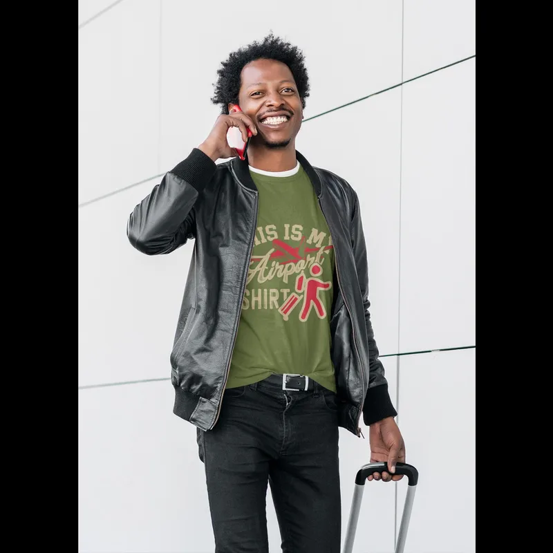Green t-shirt reading This is my Airport Shirt in a vintage-style font, worn with a black jacket